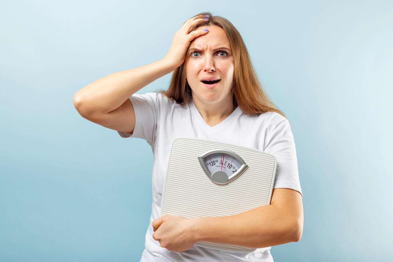 Женщина держит весы в испуге