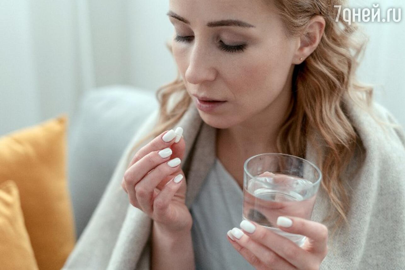 Женщина пьет таблетку при температуре