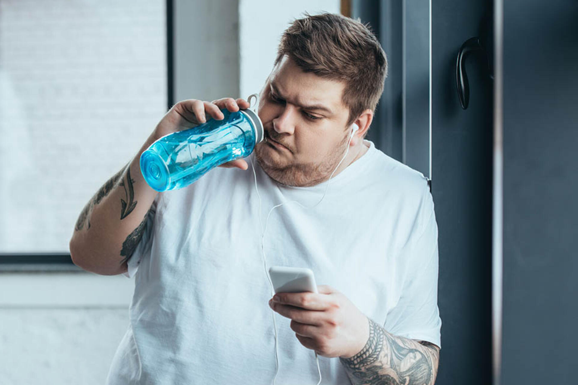 мужчина с лишним весом пьет воду