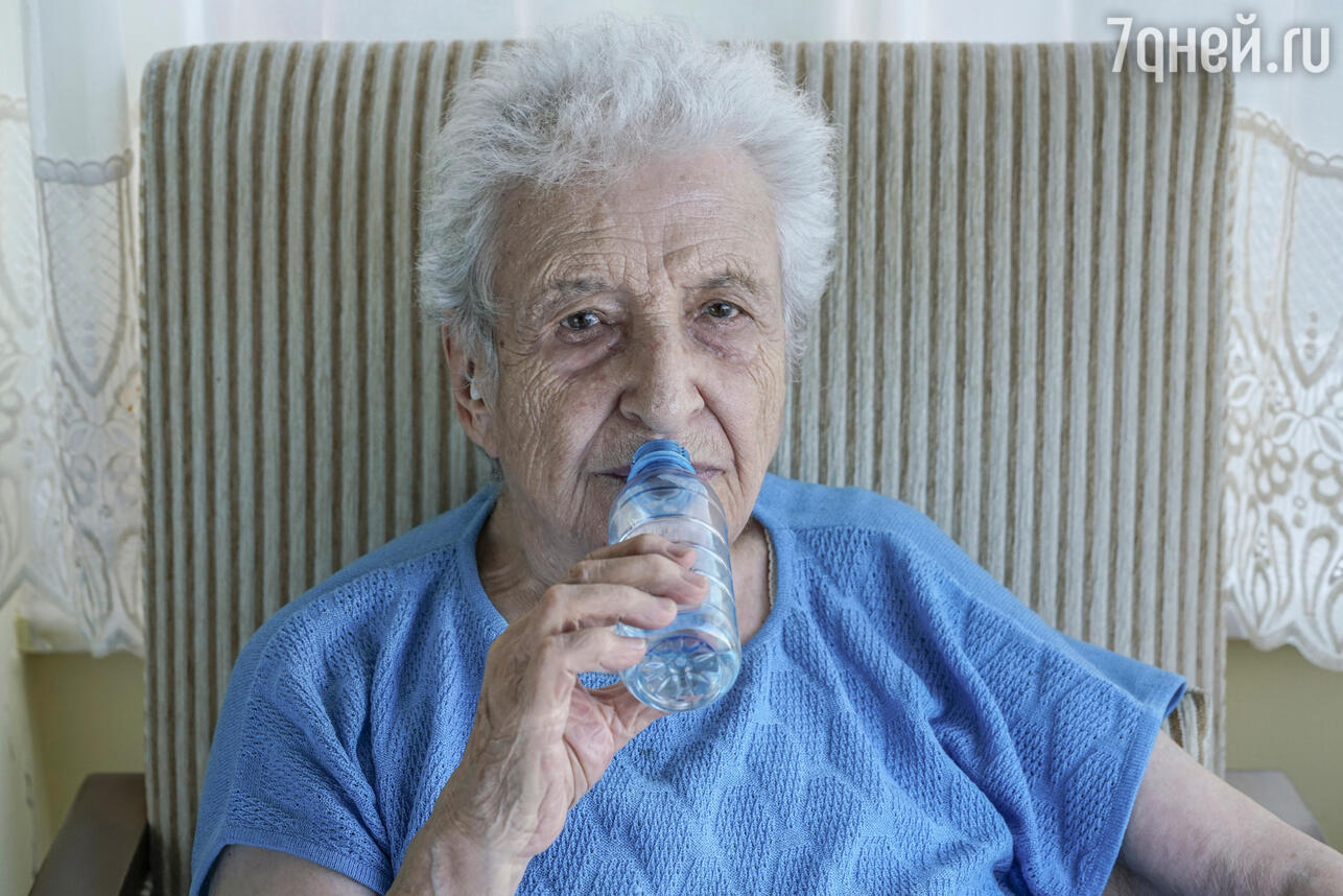 Пожилая женщина пьет воду